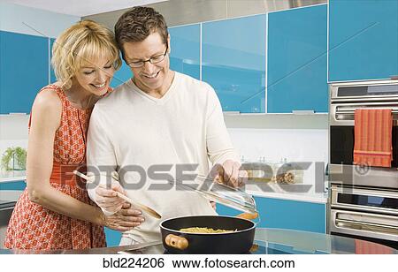 Stock Photograph - Caucasian couple cooking in kitchen. Fotosearch