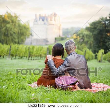 Stock Photo - Caucasian couple enjoying picnic in vineyard. Fotosearch