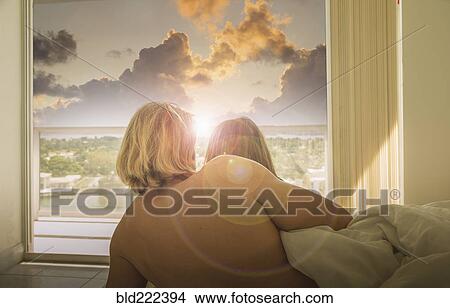 Caucasian couple in bed watching sunset at window View Large Photo Image Picture - Caucasian couple in bed watching sunset at window. Fotosearch