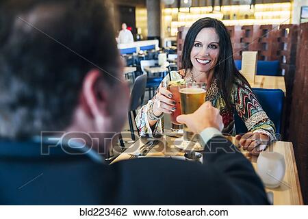 Stock Image - Caucasian couple toasting with cocktails in restaurant. Fotosearch
