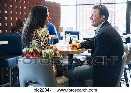 Stock Image - Caucasian couple with cocktails talking in bar. Fotosearch