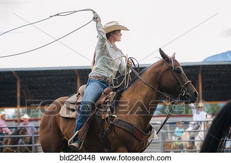 Stock Photo - Caucasian cowgirl twirling lasso in rodeo. Fotosearch