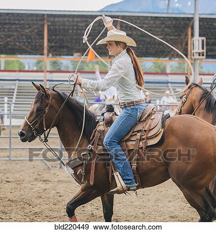 Stock Photo - Caucasian cowgirl twirling lasso in rodeo. Fotosearch