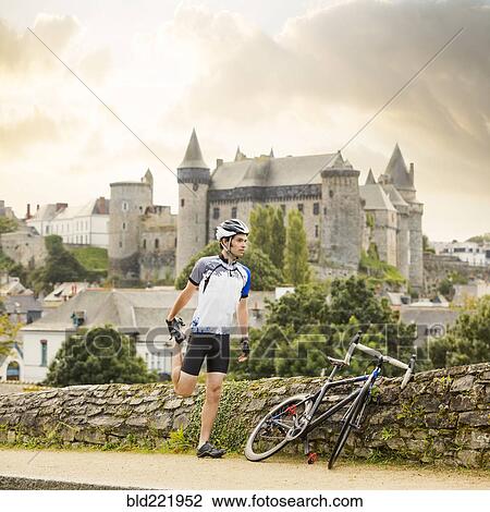 Stock Image - Caucasian cyclist stretching outdoors. Fotosearch