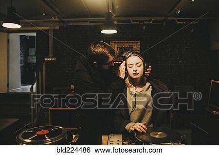 Caucasian dj holding headphones on woman View Large Photo Image Stock Photograph - Caucasian dj holding headphones on woman. Fotosearch