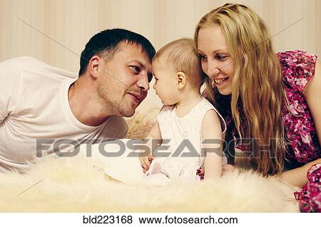 Caucasian family relaxing in bed View Large Photo Image Stock Photo - Caucasian family relaxing in bed. Fotosearch