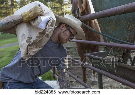 Stock Photography - Caucasian farmer carrying bag feeding animals. Fotosearch