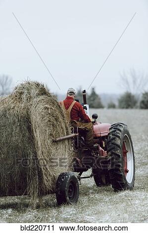 Stock Image - Caucasian farmer driving tractor in field. Fotosearch