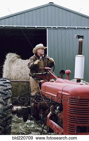 Stock Photo - Caucasian farmer driving tractor on farm. Fotosearch