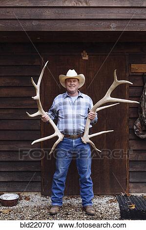 Caucasian farmer holding antlers on front porch View Large Photo Image Stock Photo - Caucasian farmer holding antlers on front porch. Fotosearch