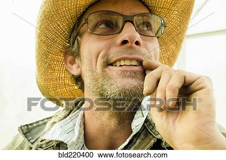 Stock Image - Caucasian farmer wearing straw hat outdoors. Fotosearch