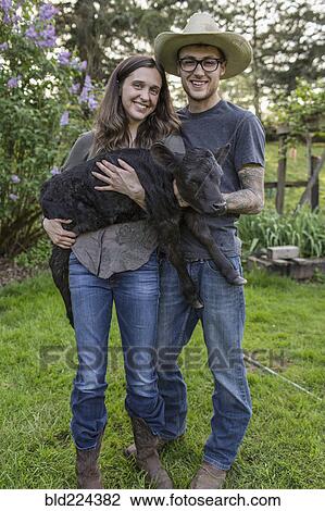 Stock Image - Caucasian farmers carrying calf. Fotosearch