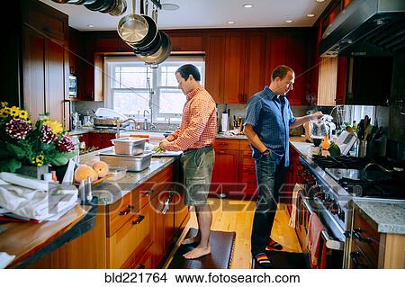 Caucasian gay couple cooking in kitchen View Large Photo Image Picture - Caucasian gay couple cooking in kitchen. Fotosearch