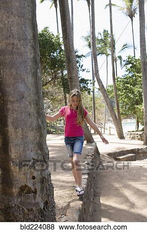 Stock Photo - Caucasian girl balancing on wall at beach. Fotosearch