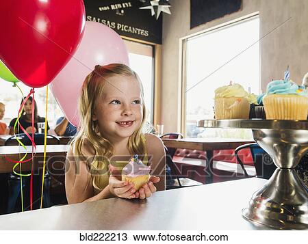 Stock Image - Caucasian girl celebrating birthday in cafe. Fotosearch