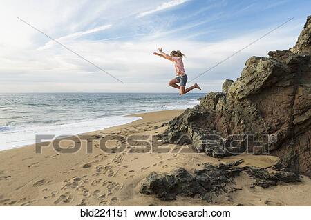 Caucasian girl jumping off rocks at beach View Large Photo Image Stock Image - Caucasian girl jumping off rocks at beach. Fotosearch
