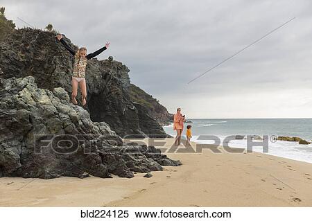Caucasian girl jumping off rocks at beach View Large Photo Image Stock Photography - Caucasian girl jumping off rocks at beach. Fotosearch