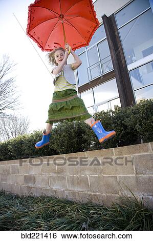 Stock Photograph - Caucasian girl jumping with umbrella. Fotosearch