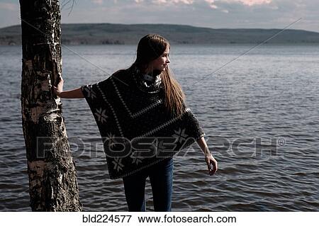 Caucasian girl leaning on tree trunk at lake View Large Photo Image Stock Photo - Caucasian girl leaning on tree trunk at lake. Fotosearch