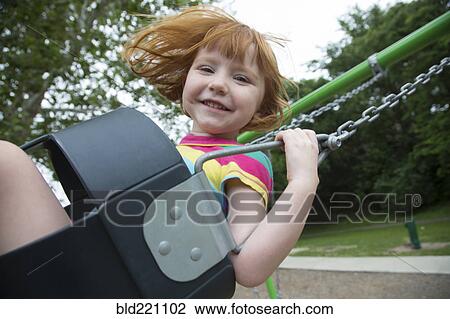 Stock Image - Caucasian girl playing on swing. Fotosearch