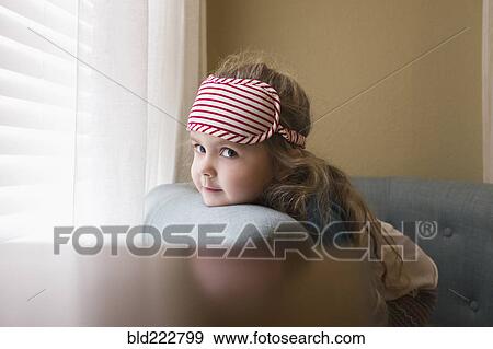 Stock Photo - Caucasian girl resting chin on sofa near window. Fotosearch