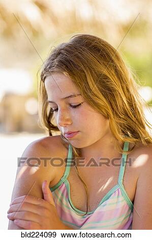 Caucasian girl rubbing arm outdoors View Large Photo Image Stock Photo - Caucasian girl rubbing arm outdoors. Fotosearch
