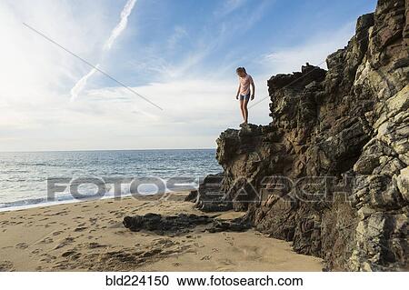 Caucasian girl standing on rocks at beach View Large Photo Image Stock Image - Caucasian girl standing on rocks at beach. Fotosearch