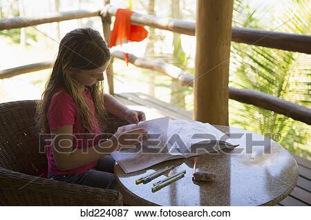 Stock Photo - Caucasian girl turning pages of sketchpad on patio. Fotosearch