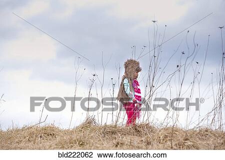 Stock Image - Caucasian girl walking on hilltop. Fotosearch