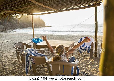 Picture - Caucasian girl with arms raised in chair at beach. Fotosearch