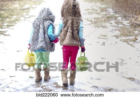 Stock Image - Caucasian girls holding hands in snow. Fotosearch