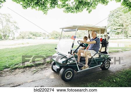 Caucasian grandfather and grandson driving golf cart on course View Large Photo Image Picture - Caucasian grandfather and grandson driving golf cart on course. Fotosearch