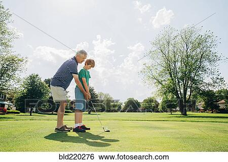Caucasian grandfather teaching grandson golf on course View Large Photo Image Stock Photograph - Caucasian grandfather teaching grandson golf on course. Fotosearch