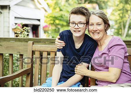 Stock Image - Caucasian grandmother and grandson smiling in backyard. Fotosearch