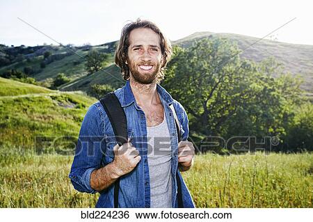Stock Photograph - Caucasian hiker standing in grass on mountain. Fotosearch