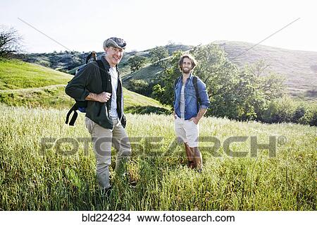 Picture - Caucasian hikers standing in grass on mountain. Fotosearch