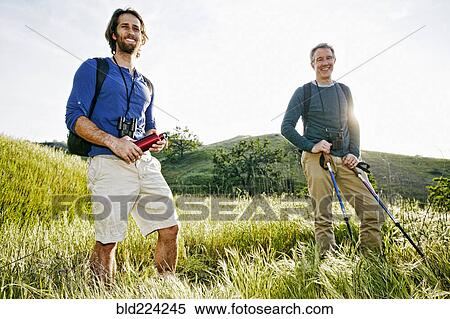 Stock Photography - Caucasian hikers standing in grass on mountain. Fotosearch