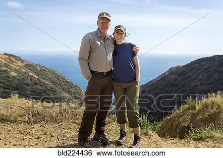 Stock Photograph - Caucasian man and daughter hugging on mountain. Fotosearch