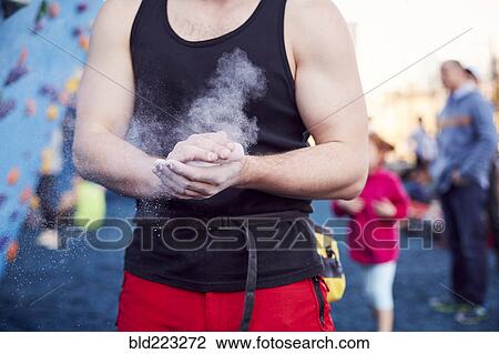 Stock Image - Caucasian man chalking hands at outdoor climbing wall. Fotosearch
