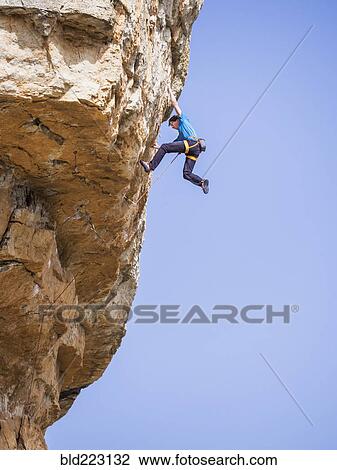 Stock Image - Caucasian man climbing rock. Fotosearch