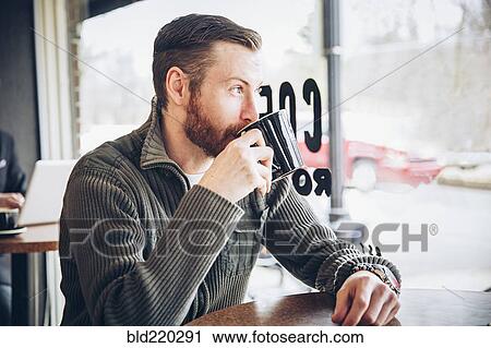 Stock Image - Caucasian man drinking coffee in cafe. Fotosearch