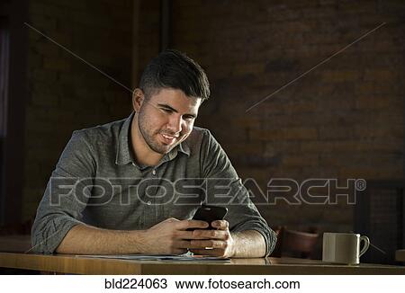 Caucasian man drinking coffee in cafe holding cell phone View Large Photo Image Stock Image - Caucasian man drinking coffee in cafe holding cell phone. Fotosearch