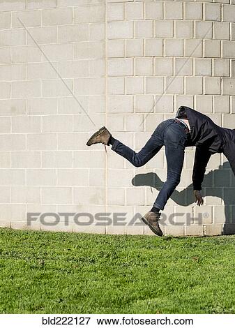 Caucasian man falling near brick wall View Large Photo Image Stock Photo - Caucasian man falling near brick wall. Fotosearch