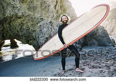 Caucasian man holding surfboard at beach View Large Photo Image Stock Image - Caucasian man holding surfboard at beach. Fotosearch