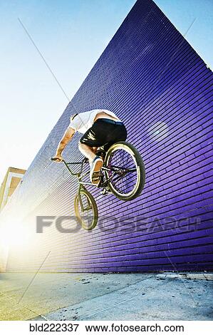 Stock Photo - Caucasian man jumping on BMX bike. Fotosearch