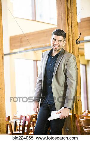 Caucasian man leaning on beam in cafe holding paperwork View Large Photo Image Stock Photography - Caucasian man leaning on beam in cafe holding paperwork. Fotosearch