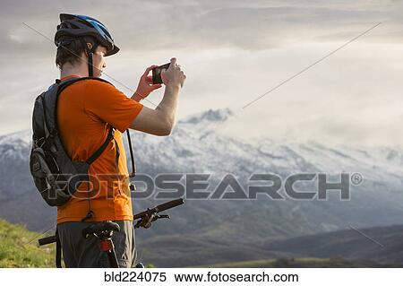 Caucasian man on mountain bike photographing scenic view View Large Photo Image Stock Photography - Caucasian man on mountain bike photographing scenic view. Fotosearch