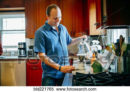 Stock Photography - Caucasian man pouring coffee in kitchen. Fotosearch