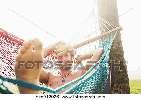 Stock Photograph - Caucasian man relaxing in hammock. Fotosearch