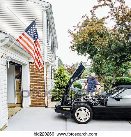 Stock Photograph - Caucasian man repairing car in driveway. Fotosearch